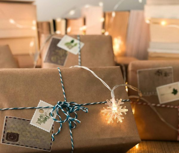 Warm holiday scene with wrapped gifts, a book, and twinkling lights for Christmas inspiration.
